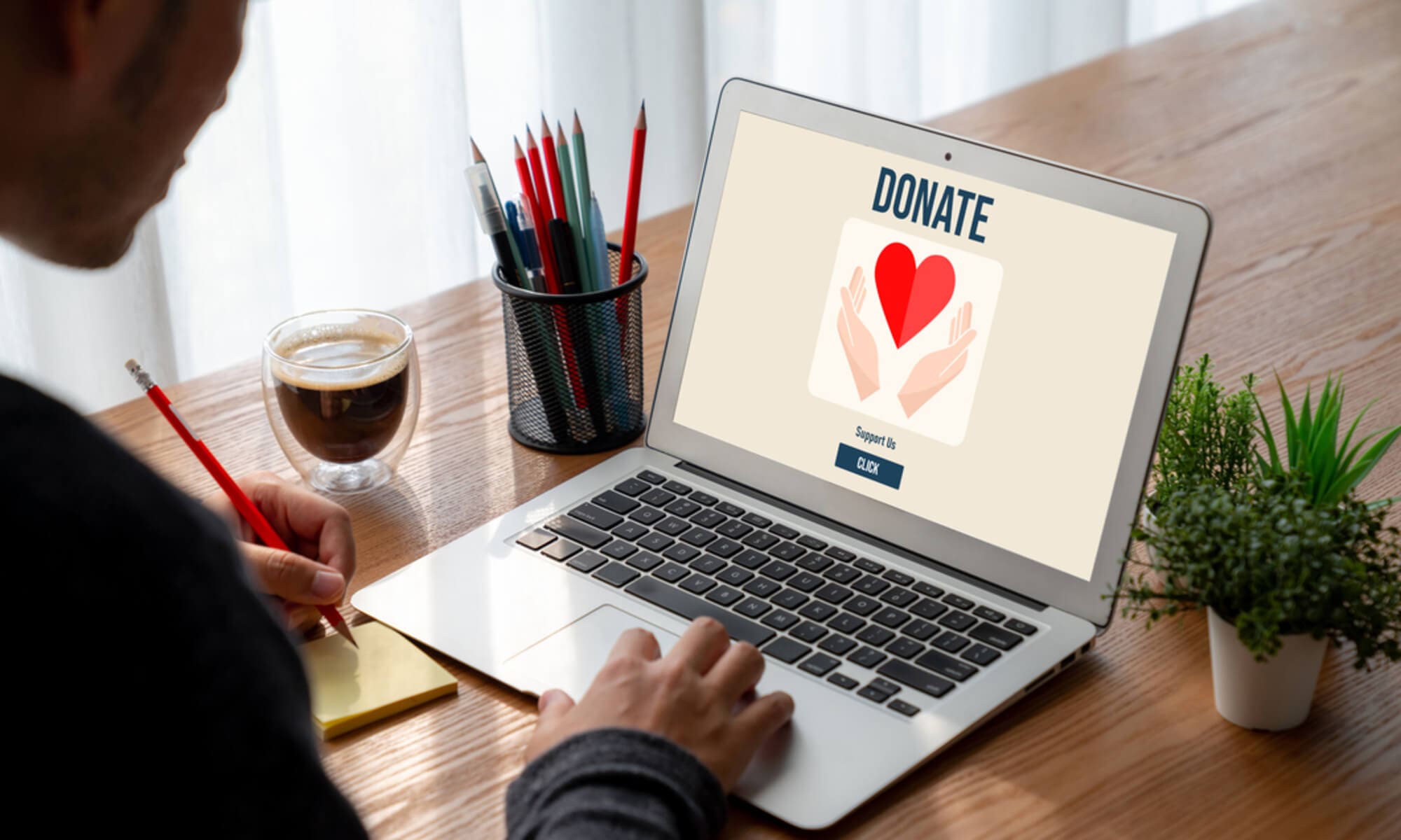 This image shows a man donating to a nonprofit on his computer.
